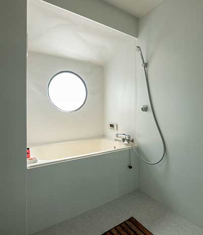 白を基調とした丸い窓のある浴室
