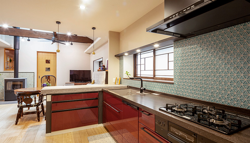 壁に和風なデザインのタイルが貼られている赤いパネルのキッチン。