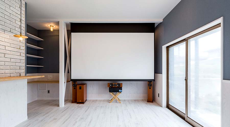 5.1chサラウンドの音響システムと大きなスクリーンで大迫力の映画鑑賞を楽しめる青い壁と白い床で海辺のカフェのようなリビング空間。